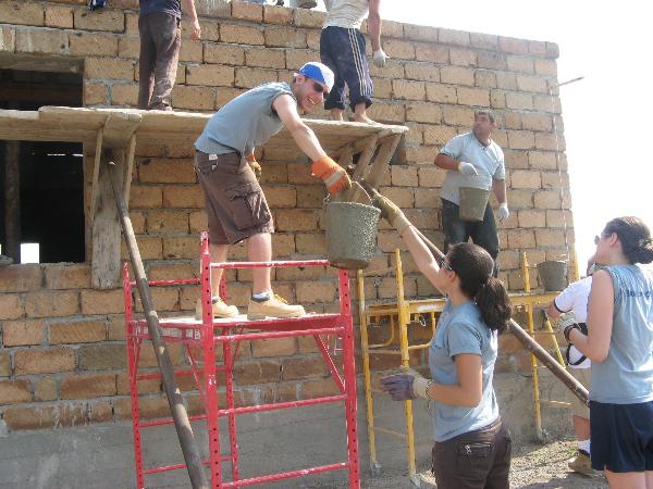 Fuller Center volunteers passing buckets of concrete as they work to build a home with a family in Armenia